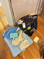 Group view of hair styling tools, heating pads, eye masks and storage bag on floor