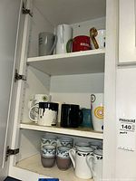 Cabinet shelves showing majority of mugs and cups