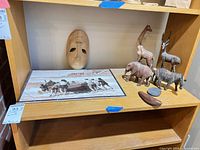 Full shelf view showing mask, five animal figures, wood bowl and stone dish