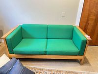 Front view of solid wood loveseat with green cushions