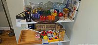 Shelf showing multiple board games, Chinese checkers board, plastic toys, teddy, rubber ducks, LEGO box partially visible
