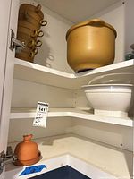 Cabinet view showing stacked handled bowls, stoneware pot, white bowl, terracotta base