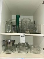 Cabinet shelves with nested glass baking dishes, round mixing bowls, stainless steel bowl, various vases