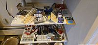 Overview of two shelves with tools, hardware, WD-40, clamp, packaged fasteners