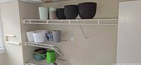 Shelf showing five top planters (mint ribbed, taupe, black) and lower shelf with additional planters plus green watering can