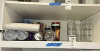 Shelf view showing glass tumblers stacked and assorted disposable cups