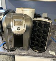 Keurig brewer, K-cup carousel, Starbucks drip maker, enamelware pot and grinder on countertop