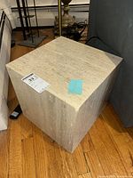 travertine cube showing top and two sides with veining and label