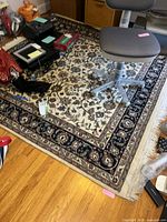 Full view of square Oriental-style rug with chair and items on top