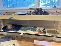 Shelf view showing ice bucket, navy tray beneath, green tray, small round tray, large round tray