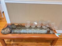 Overview of four metal trivets and eleven coupe glasses on glass-top table