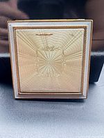 Closed compact showing guilloché sunburst lid and rope border