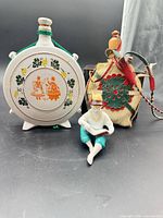 Group view of porcelain flask, straw-covered flask and reading boy figurine