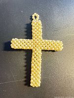 Full view of pearl bead cross pendant on dark background