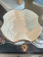 Top view of cream porcelain nut dish showing scalloped hexagonal shape, raised lattice pattern and gold rim