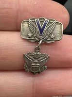 Front view showing winged V, stars, and dangling eagle charm