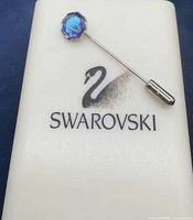 Pin in Swarovski box lid showing swan logo