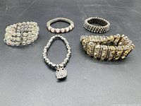 All five bracelets laid out on black surface