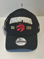 Front view showing CHAMPIONS, NBA 2019 text, Raptors logo, 9TWENTY sticker