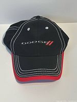Front view of black Dodge cap with red brim and white stitching