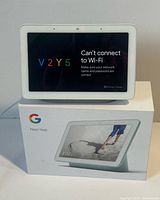 Google Nest Hub powered on atop original box, front view