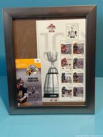 Front view of framed stamp set showing frame, stamps, booklet and Grey Cup image