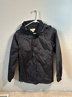 Front view of black Guru hooded jacket on hanger