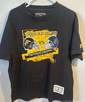 Full front view of black Hamilton Tiger-Cats Labour Day Classic t-shirt on hanger