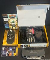 Open box showing console, accessories, UMDs, memory stick, manuals