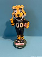 Front view of Stripes mascot doll showing uniform, football, raised finger