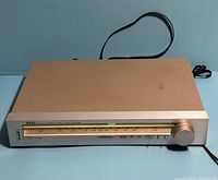 Front and top view of Akai AT-K02 tuner showing dial, controls, power cord