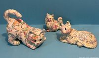 Front view of three floral porcelain cat figurines
