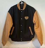 Front view showing black body, tan sleeves, Jeep chest logo, snap closure