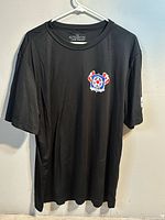 Full front view of black T-shirt on hanger