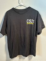 Front view of black CSI Las Vegas Unit T-shirt on hanger
