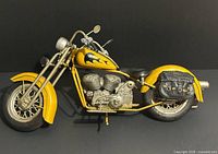 Left side view of yellow metal motorcycle model with saddlebags
