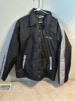 Front view of black jacket hanging, grey sleeve stripes visible