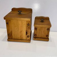 Front view of both wooden canisters with lids and metal knobs