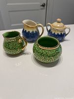Four ceramic pieces: Sudlow green/gold creamer & sugar, peach/blue lustreware creamer & lidded sugar