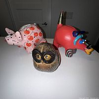 Front view of three ceramic coin banks: cherry pig, red pig, brown owl