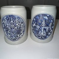 Front view of both Gerz stoneware steins showing embossed cobalt blue medallions
