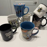 Group shot of all six mugs displaying fronts and handles
