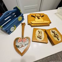 All five items laid out: blue basket, penguin plaque, heart paddle, two child plaques