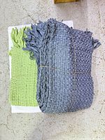 Green and blue woven recycled cotton throws stacked, twine tied