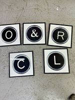 Five framed letter prints laid out showing O, &, R, C, L