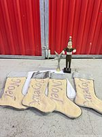 Four Noel stockings, metal star tree topper, wooden Santa figurine grouped on floor
