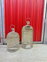 Front view showing large and small shiny silver metal cages with bar fronts and ring tops