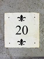 Front view of square marble plaque showing number 20, fleur-de-lis, mounting holes