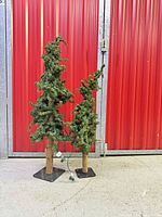 Full view of both faux trees showing height difference, bases, and attached lights