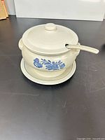 Lidded stoneware tureen on underplate with ladle, showing blue floral motif